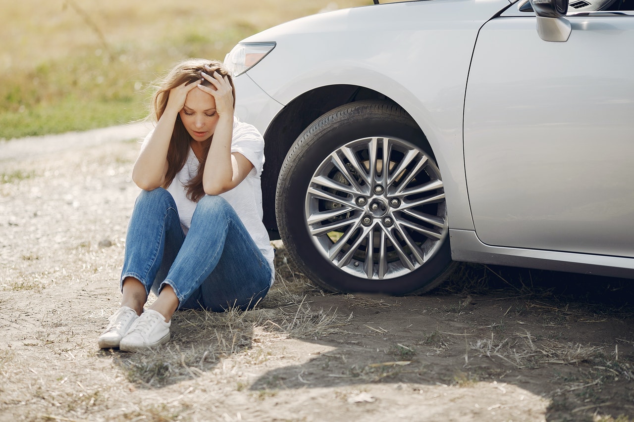 Woman sitting on the ground with both hands on her head